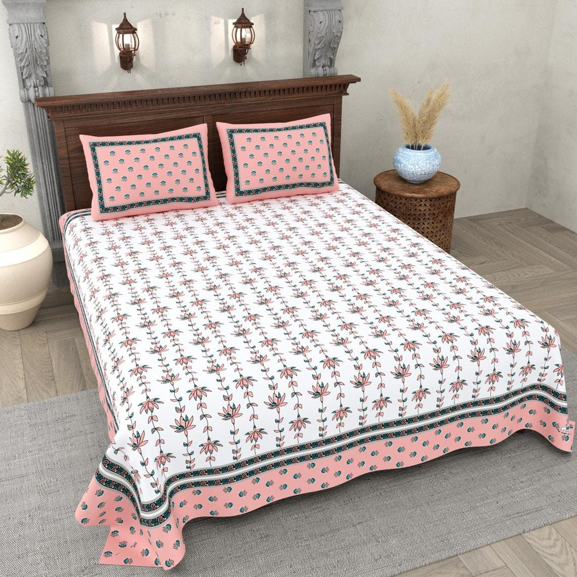 Bed with pink and white floral bedspread and pillows in a bedroom setting.