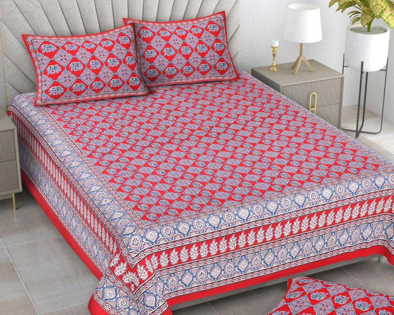 Red and white patterned bedspread set on a bed with matching pillows and a rug.