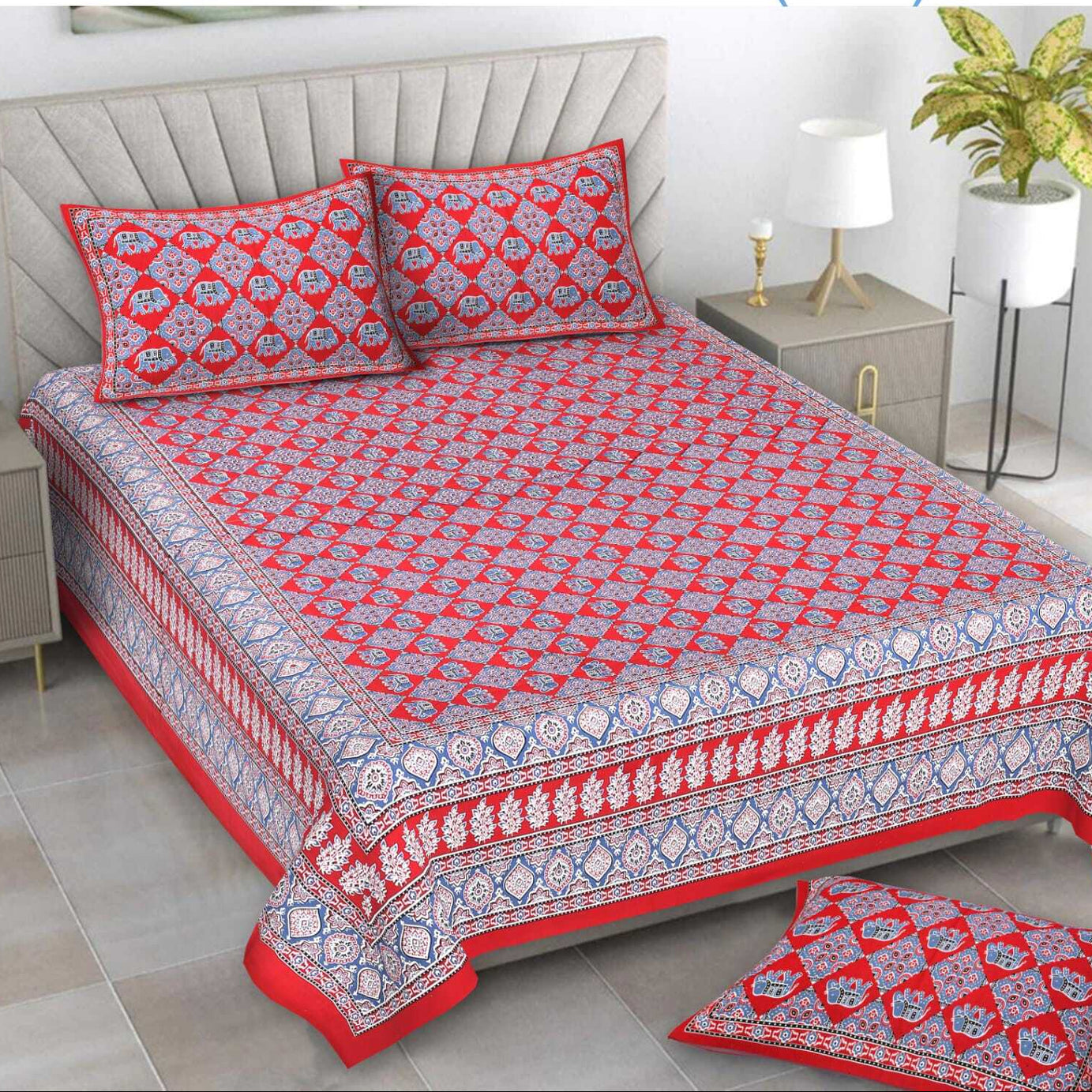 Red and white patterned bedspread set on a bed with matching pillows and a rug.