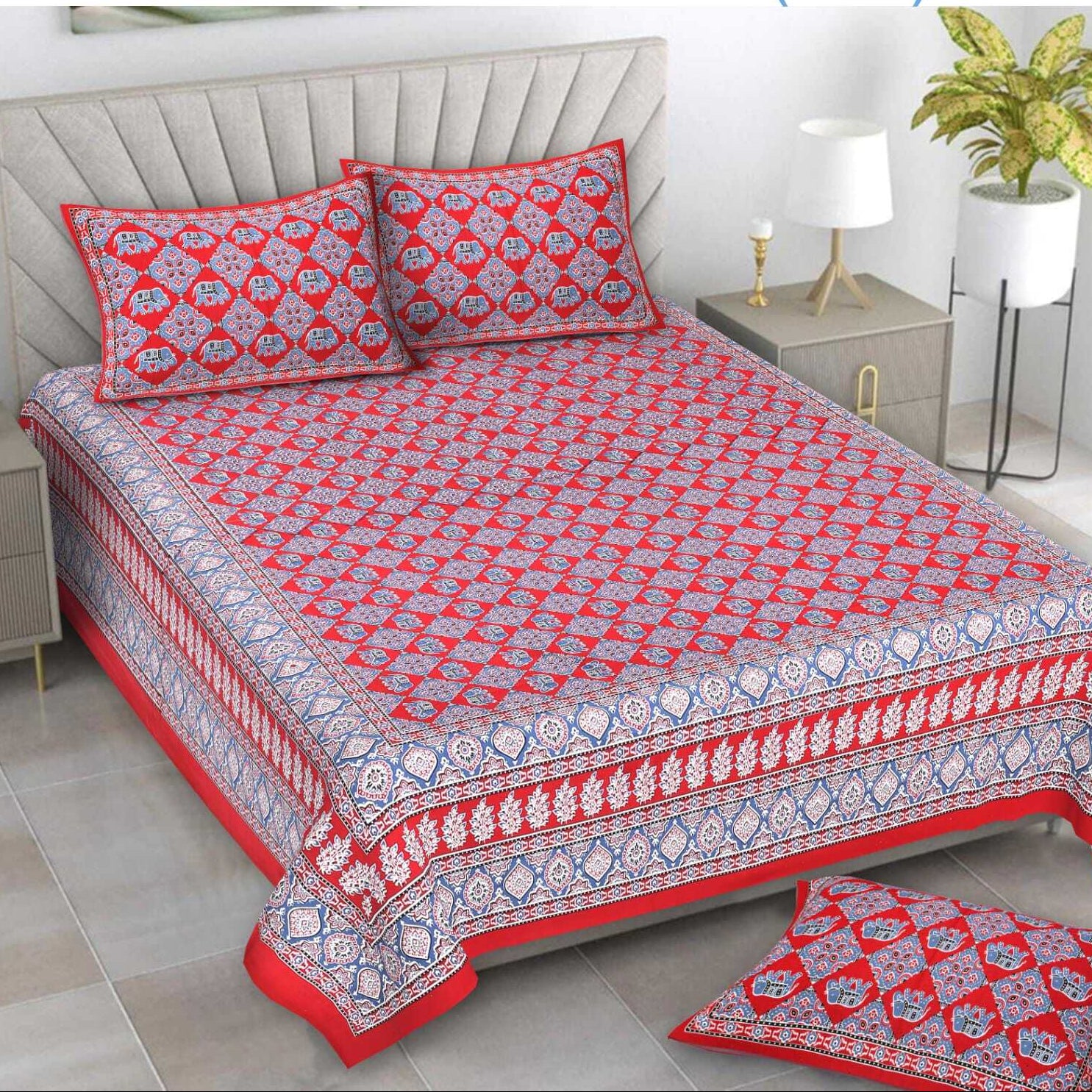Red and white patterned bedspread set on a bed with matching pillows and a rug.