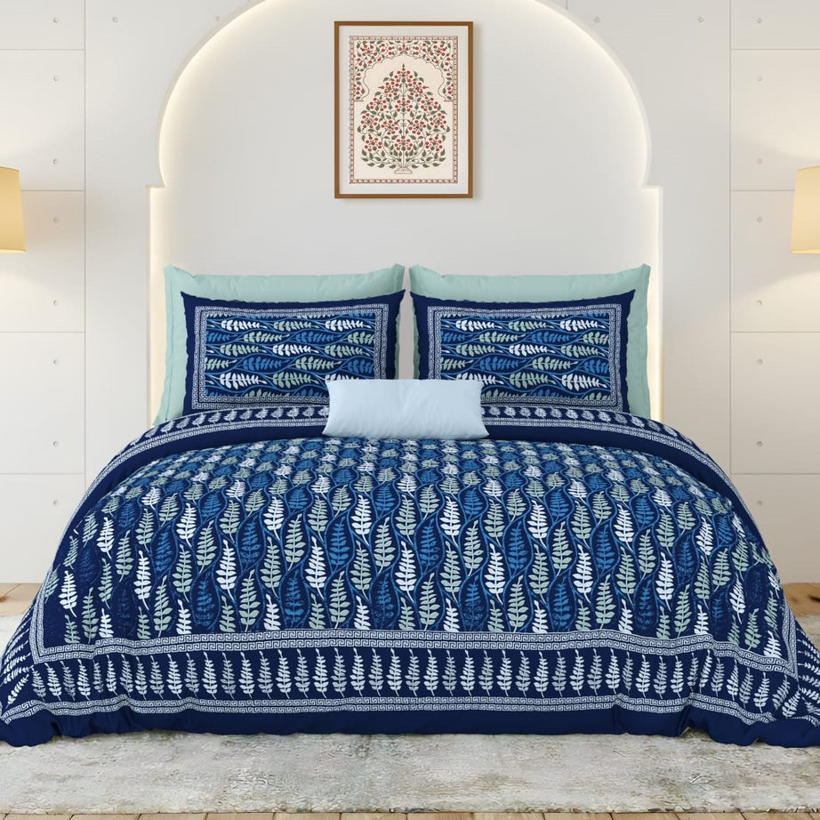 Blue and white patterned quilt set on a bed with matching pillows.