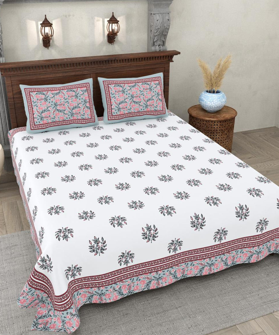 Floral patterned bedspread on a bed in a bedroom setting with decorative elements.