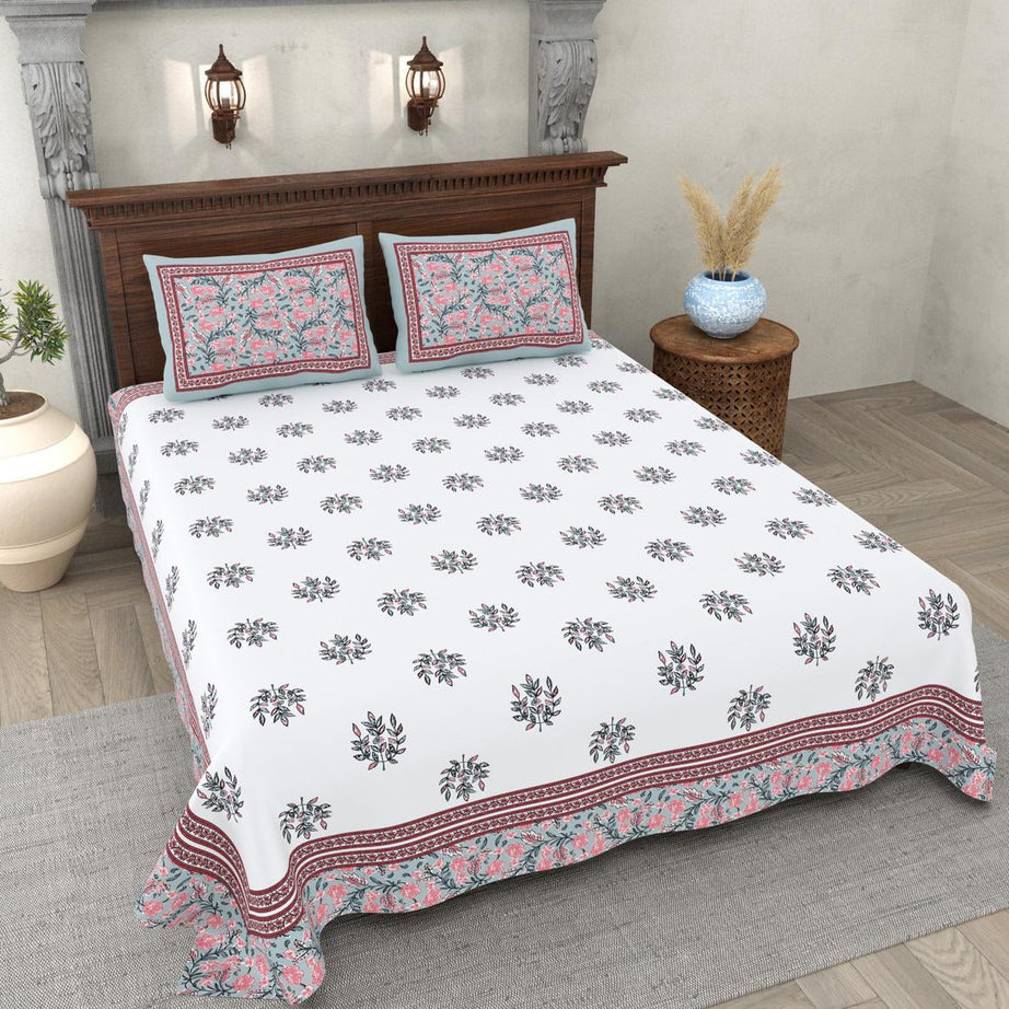 Floral patterned bedspread on a bed in a bedroom setting with decorative elements.